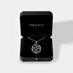 Silver necklace with an ouroboros pendant in an open black Tikalkun jewelry box on a light gray background