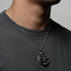 Person wearing a necklace featuring an ouroboros pendant.