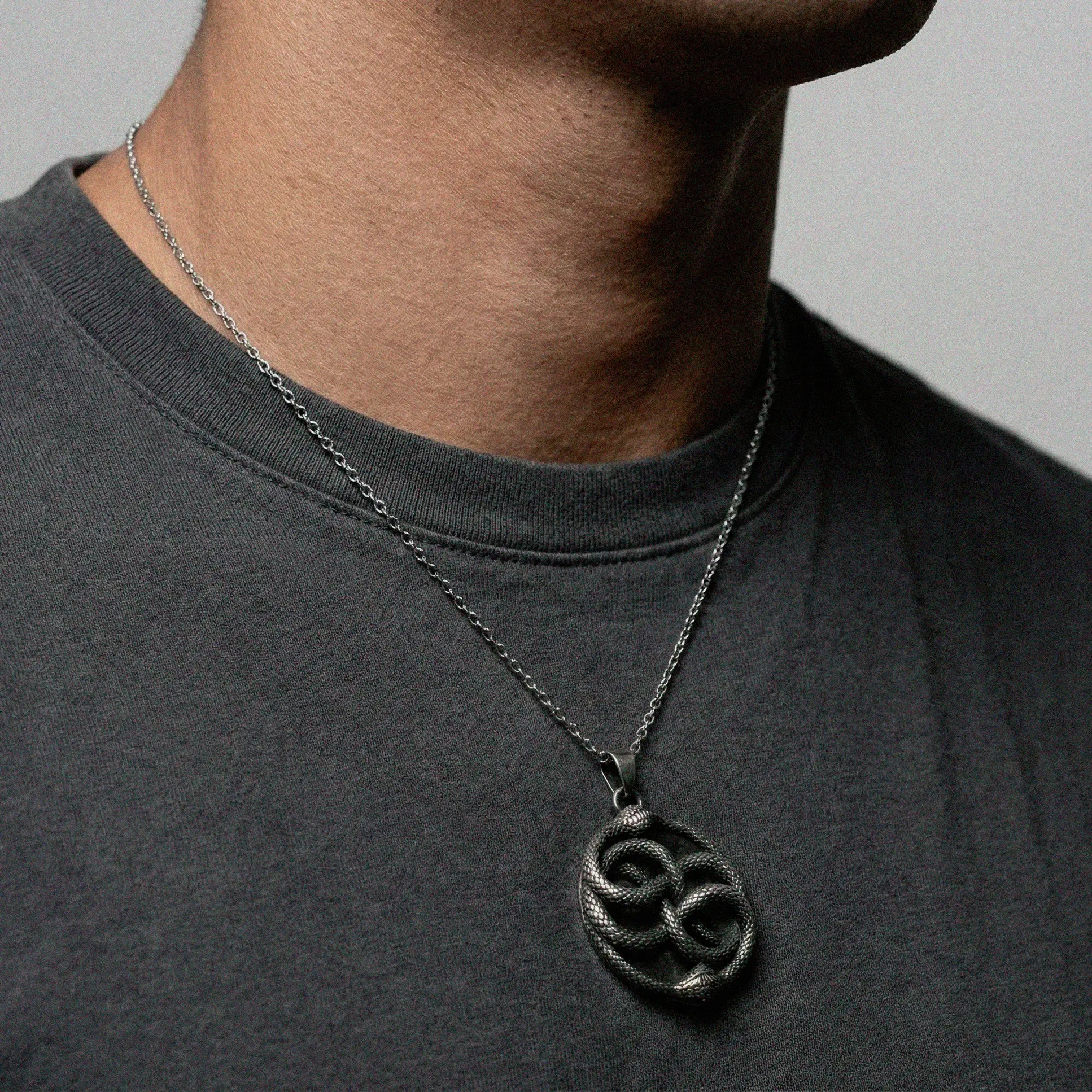 Person wearing a necklace featuring an ouroboros pendant.