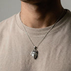 Silver pendant shaped like a MAYAN FACE on a white background