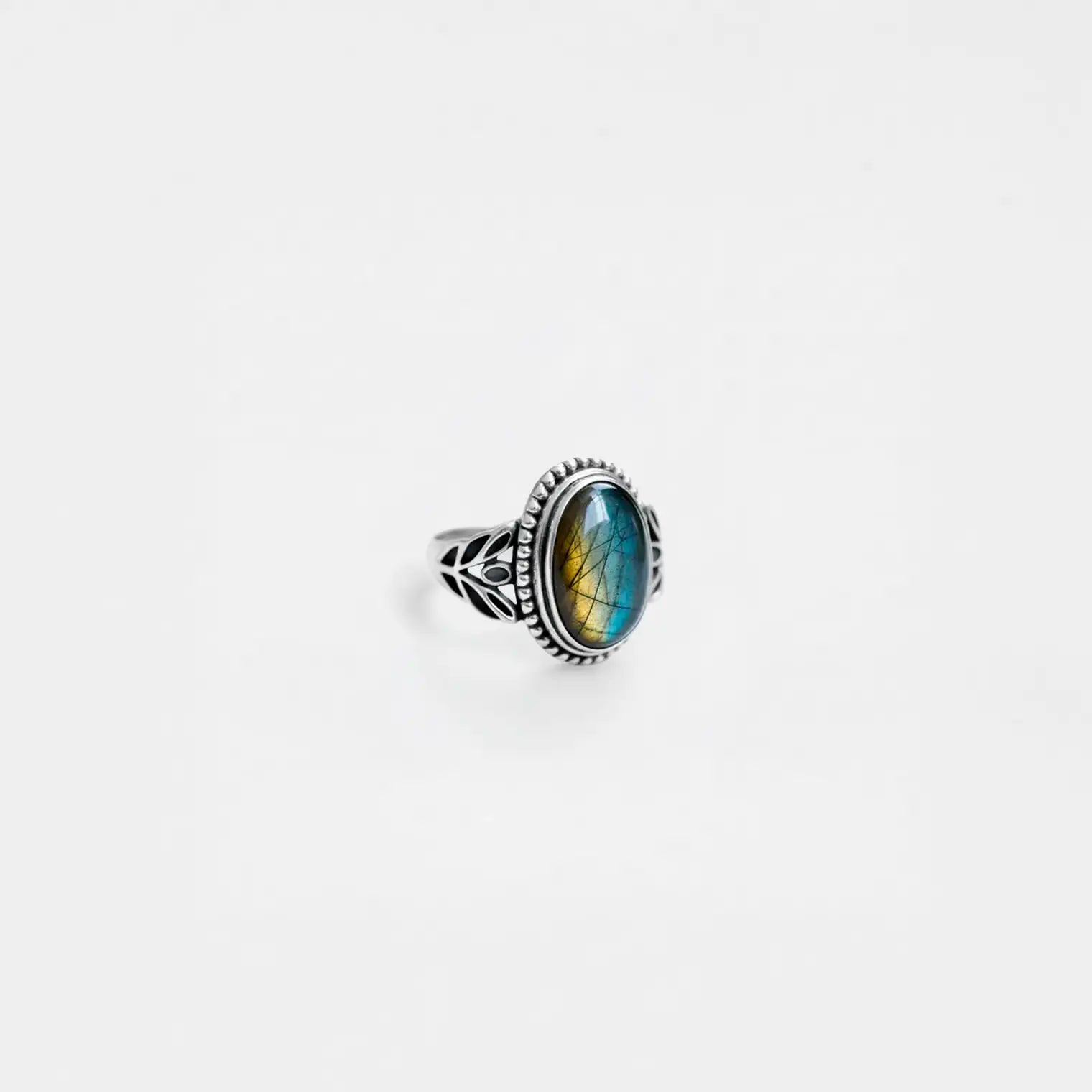 Silver ring with a labradorite gemstone on a light gray background
