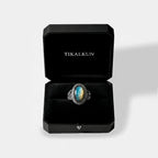 Silver ring with a laradorite stone in a black Tikalkun box on a light gray background