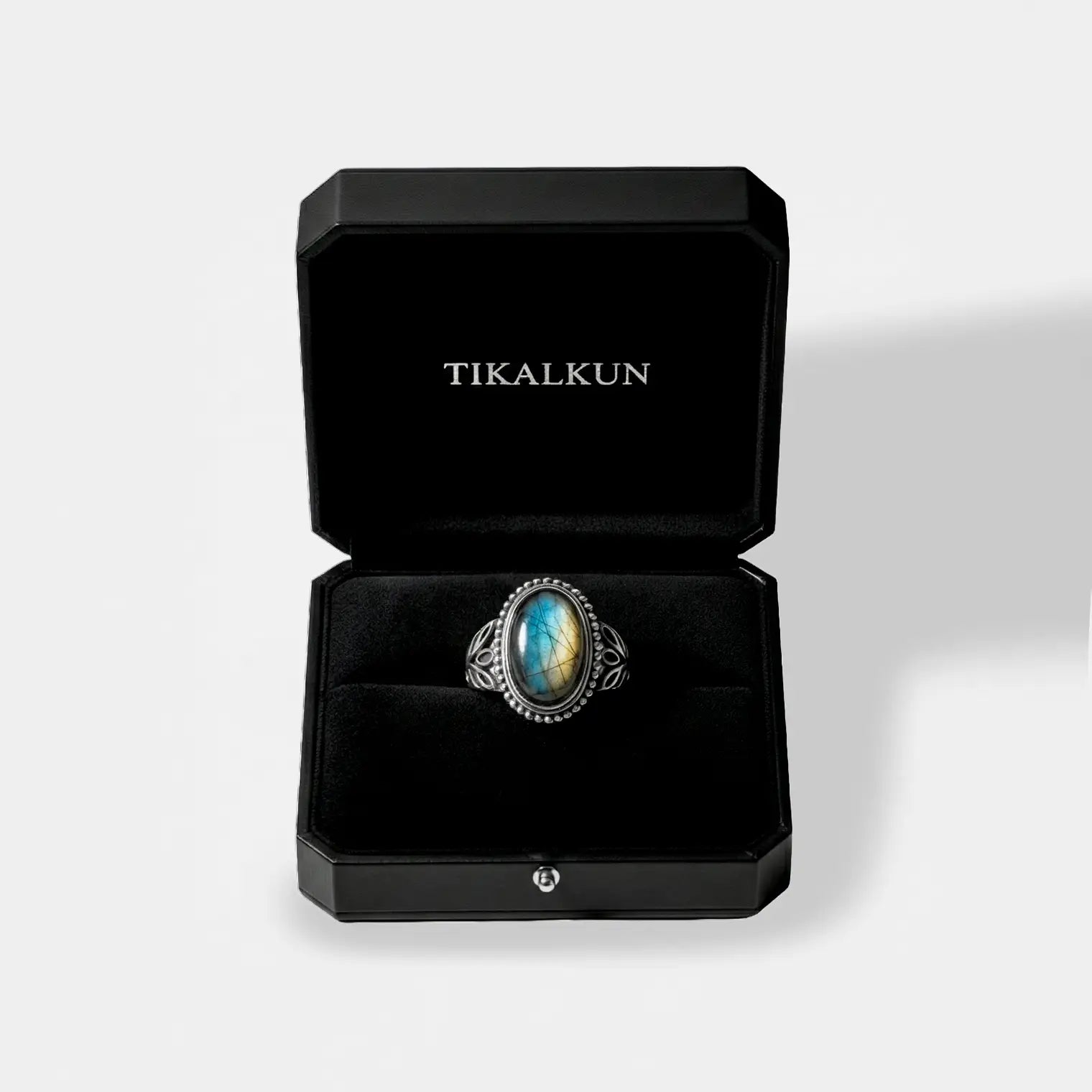 Silver ring with a laradorite stone in a black Tikalkun box on a light gray background