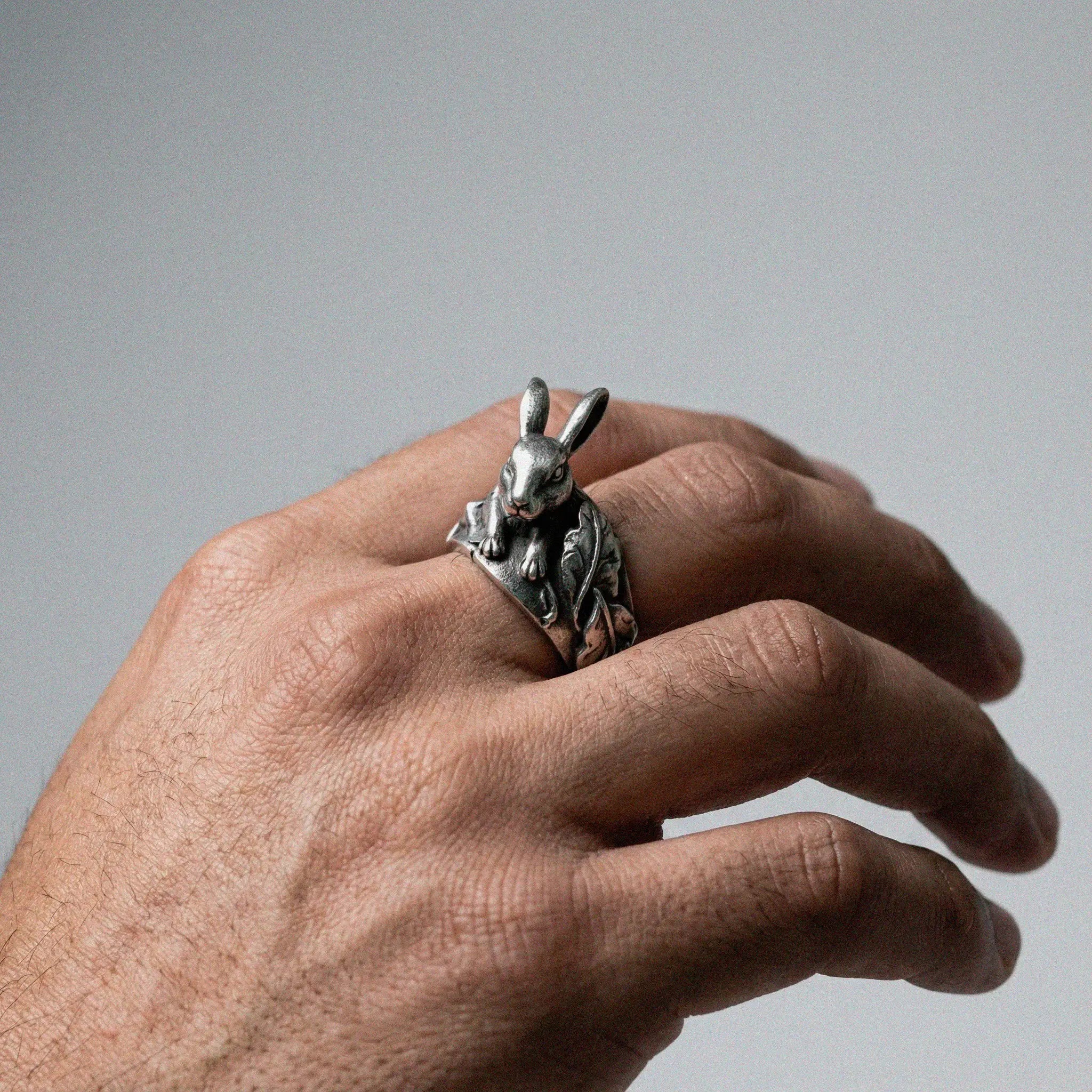 man's hand wearing a Silver rabbit ring on a white background