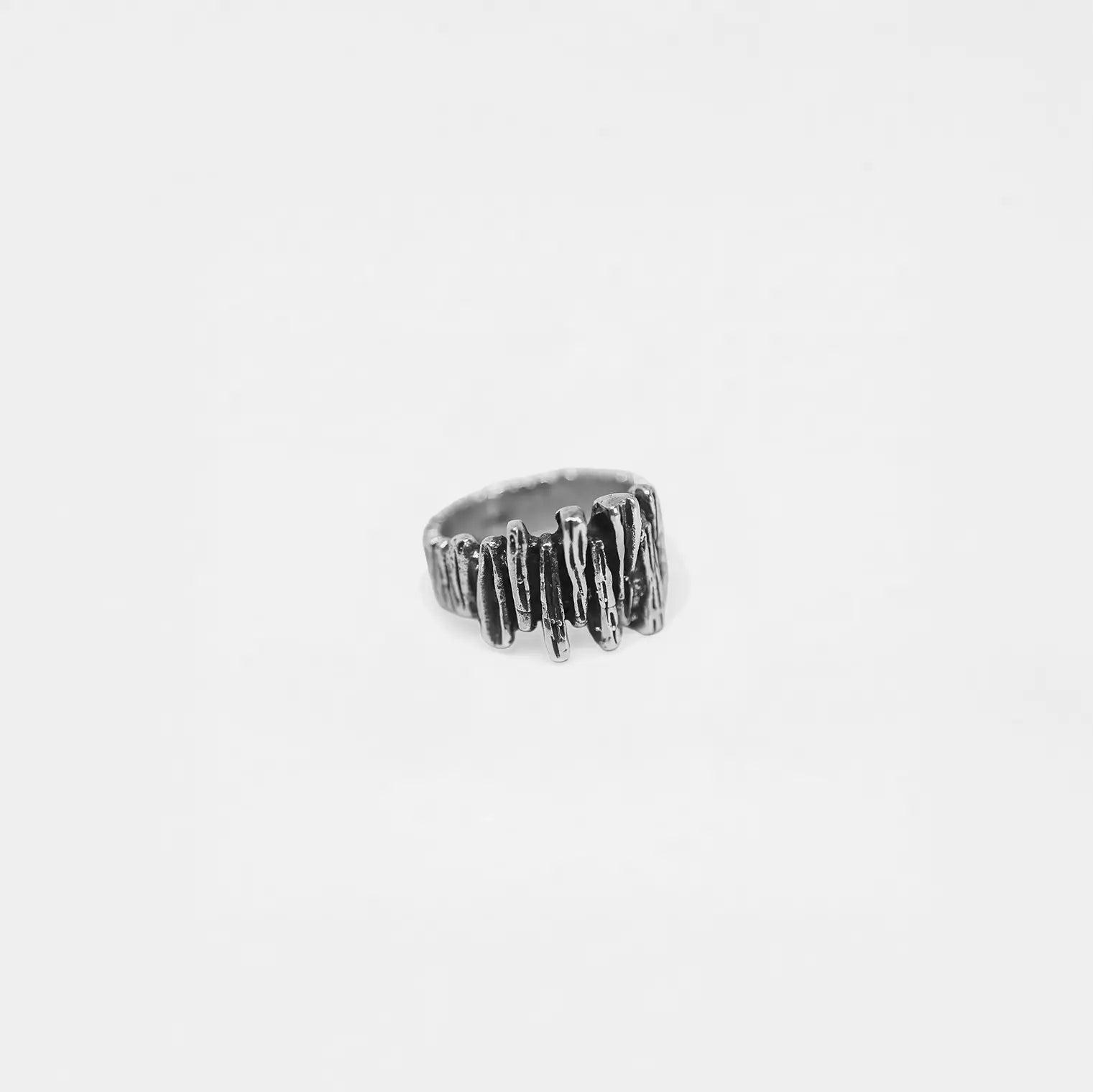 Silver ring with a rock-wall design on a white background