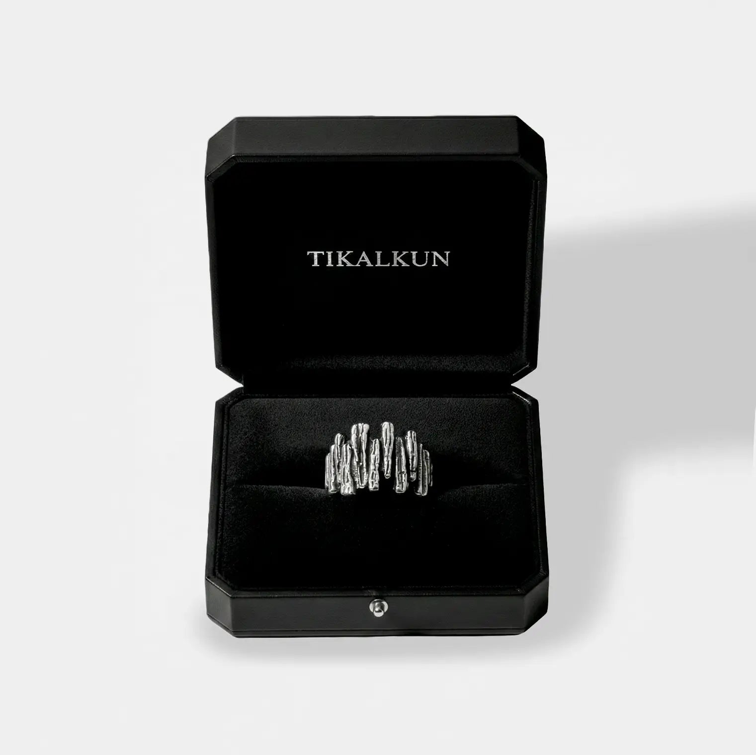 Silver rock-wall ring in a black Tikalkun jewelry box on a light gray background