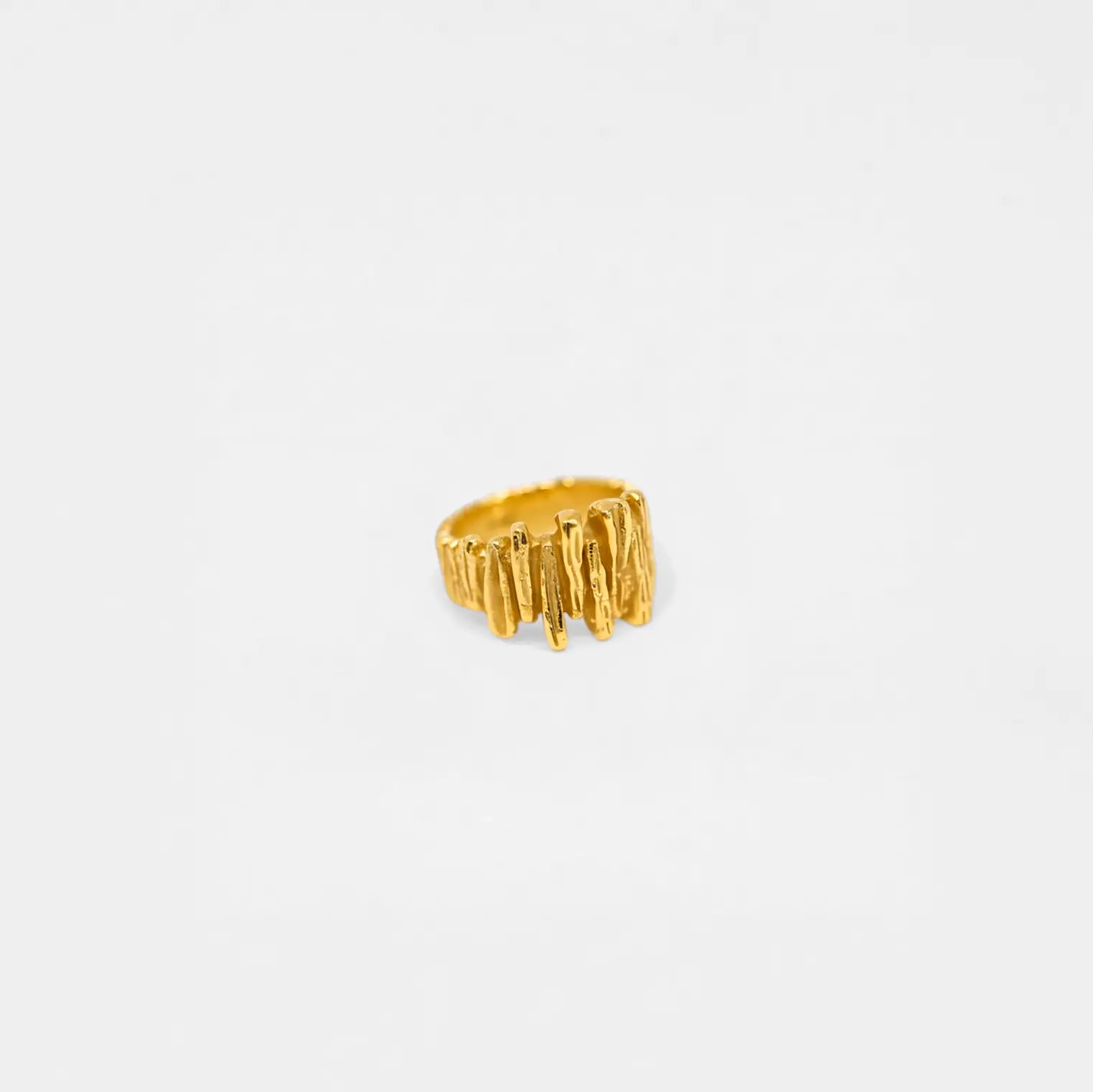 Gold rock-wall ring with a textured design on a white background