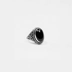 Silver ring with an obsidian stone on a light gray background