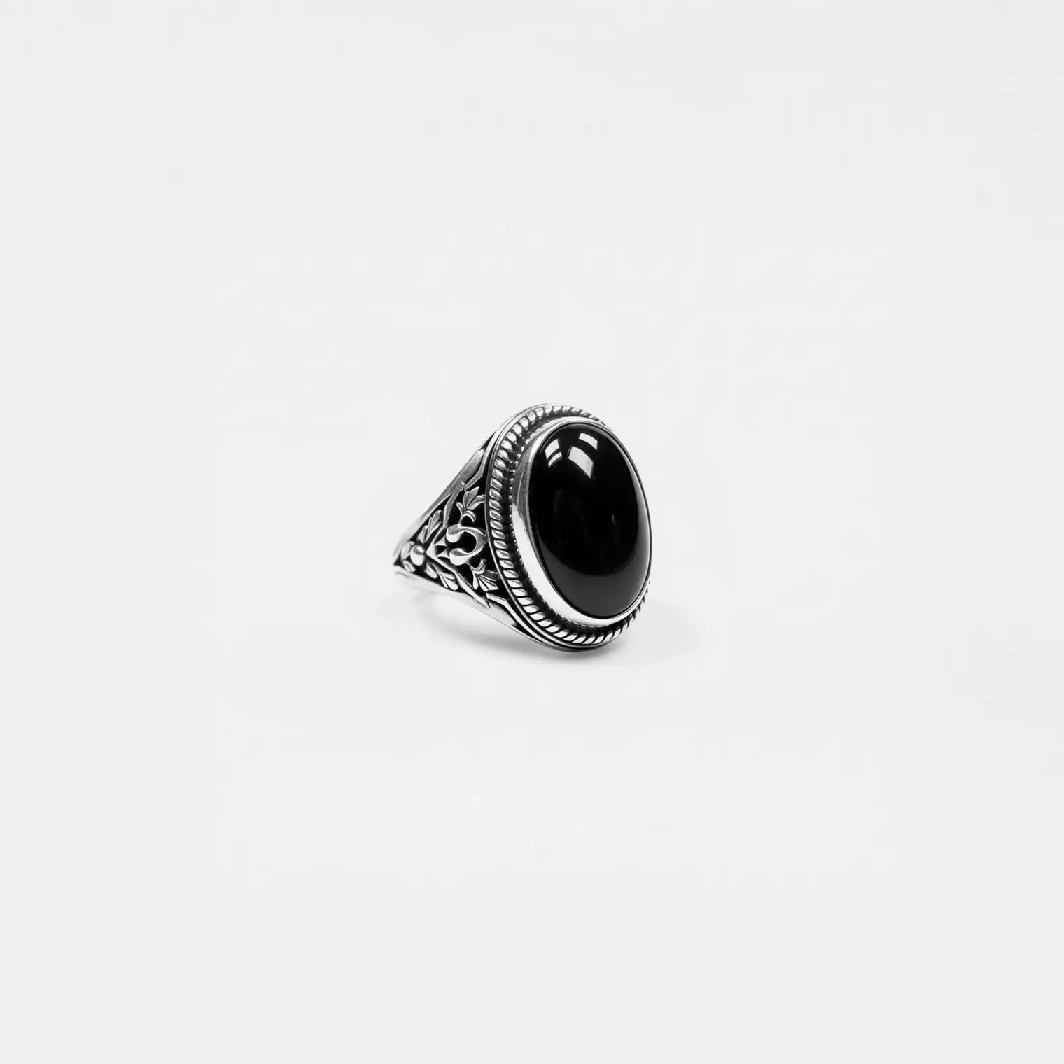 Silver ring with an obsidian stone on a light gray background