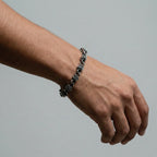 Hand wearing a roses silver bracelet on a plain background
