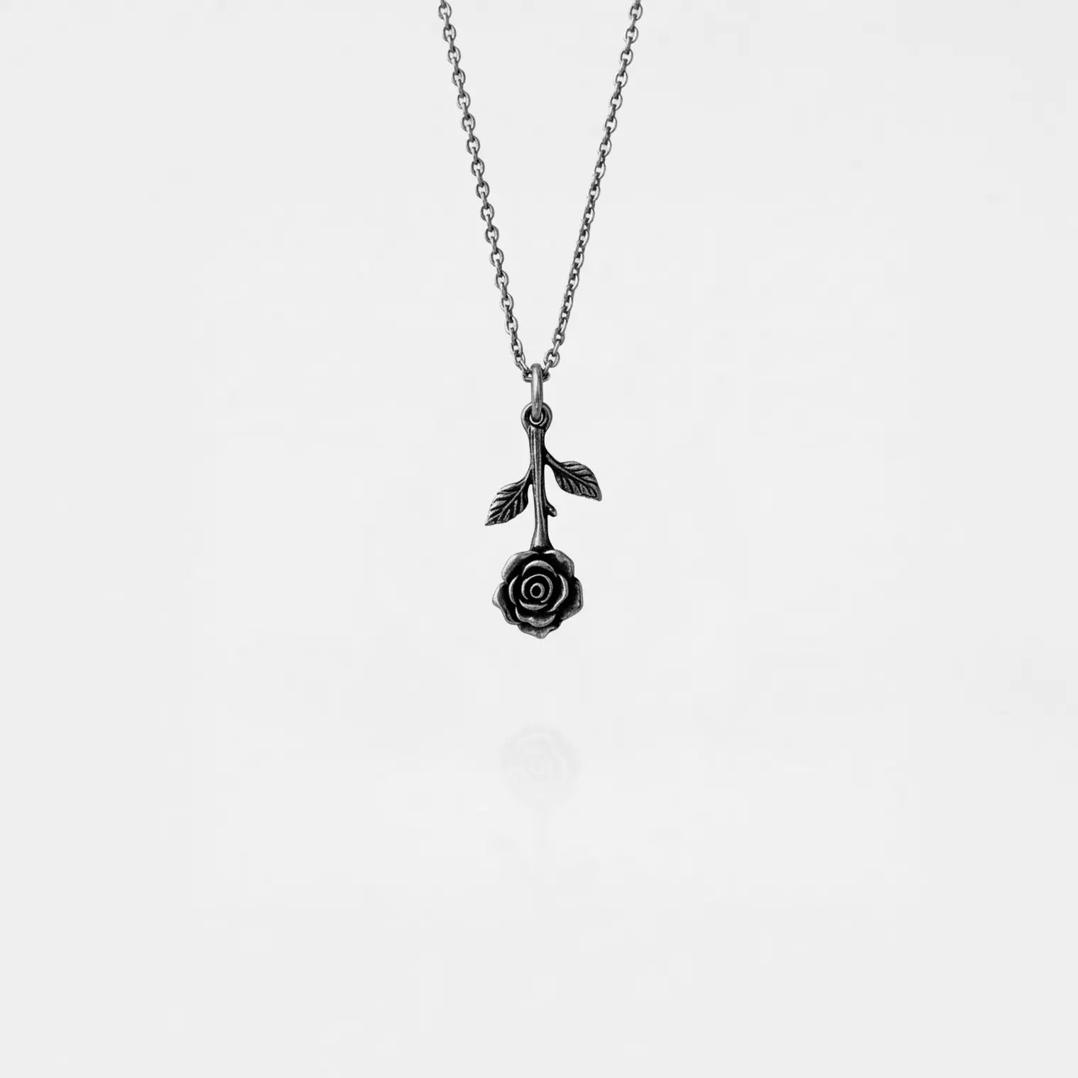 Silver necklace with a rose pendant on a light gray background