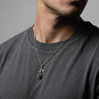 Person wearing a necklace with a rose pendant on a gray background