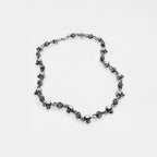 Silver necklace with floral and skull designs on a white background