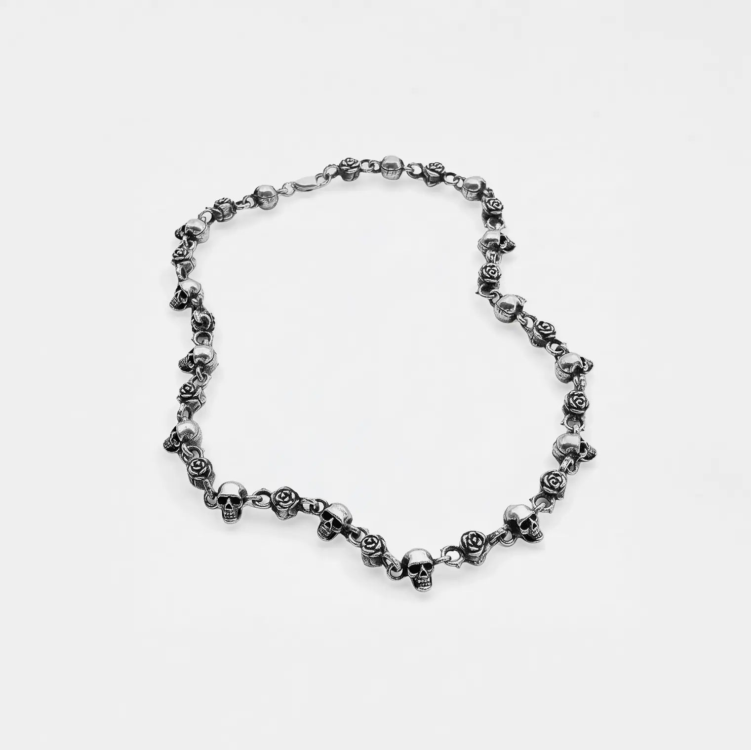 Silver necklace with floral and skull designs on a white background