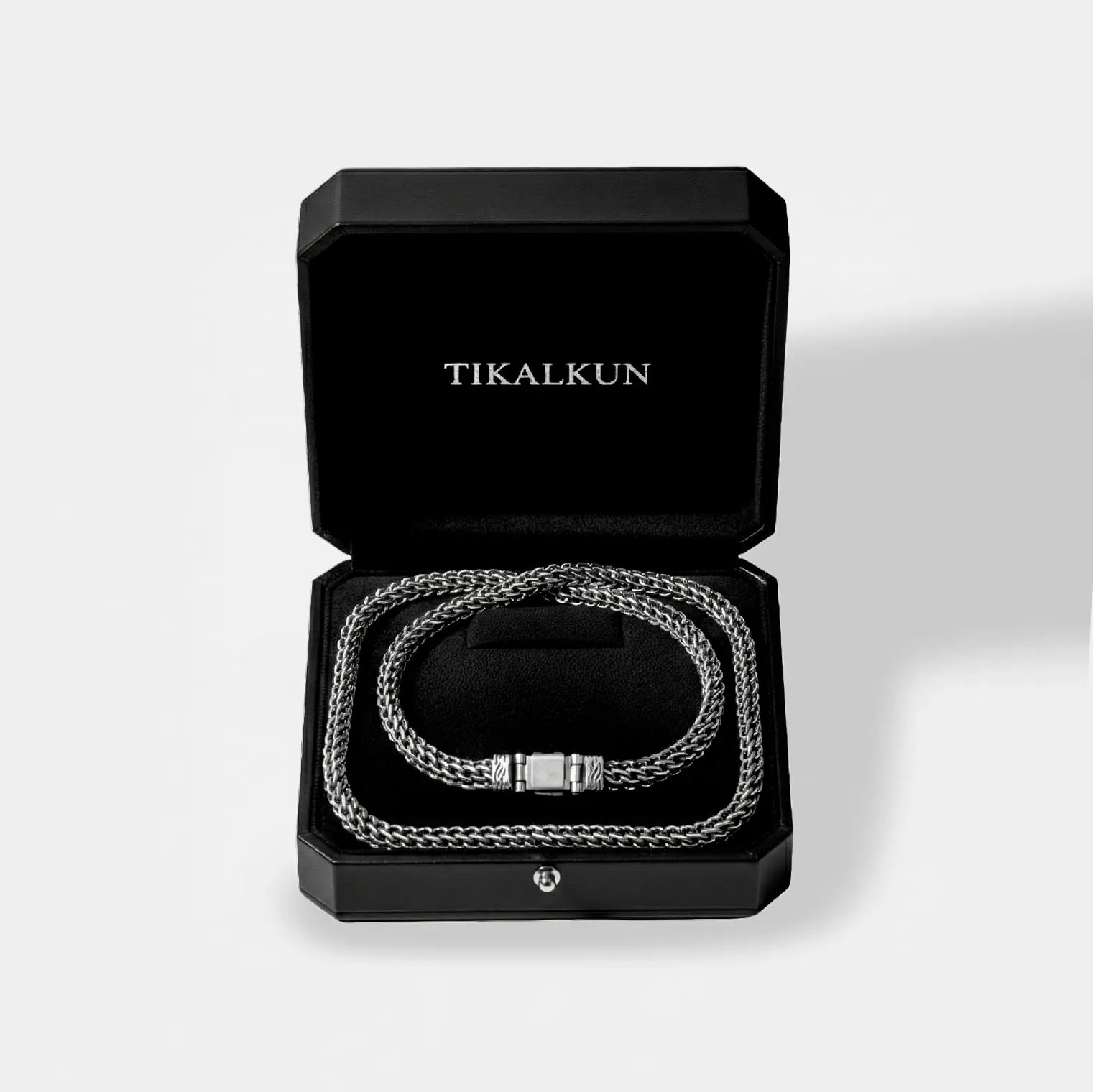Silver chain necklace in a black Tikalkun box on a light gray background