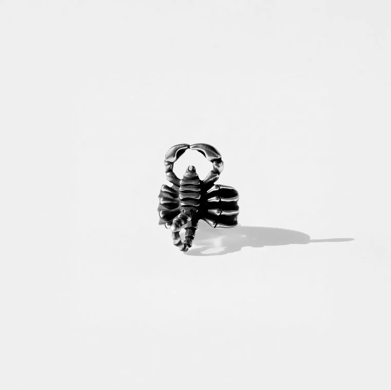 Silver scorpion-shaped ring on a white background