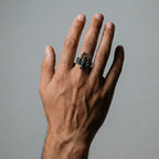 Hand wearing a silver ring with a SCORPION design on a gray background