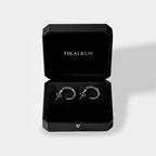 Silver earrings in a black Tikalkun jewelry box on a light gray background