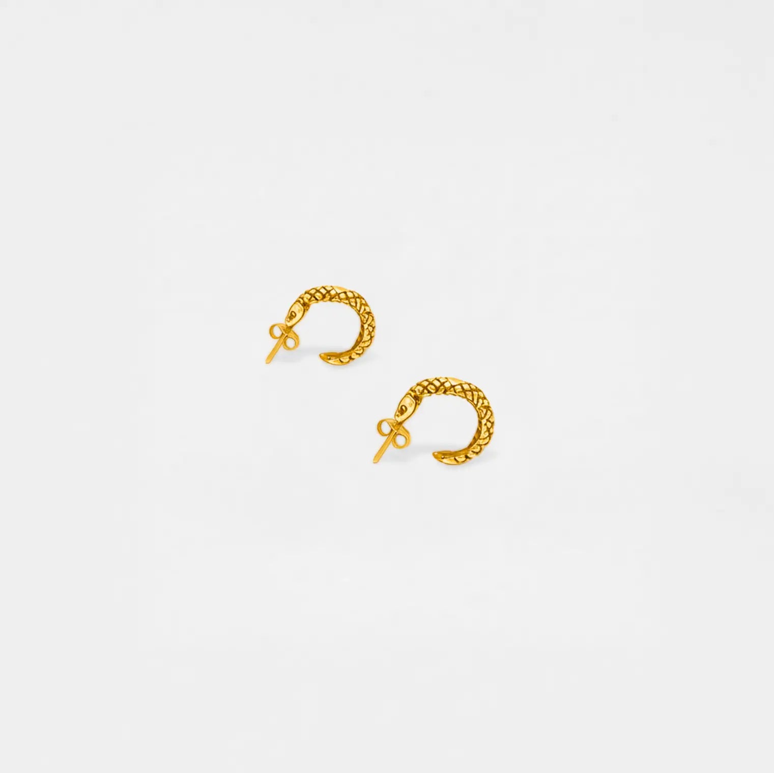 Gold hoop snake earrings on a light gray background