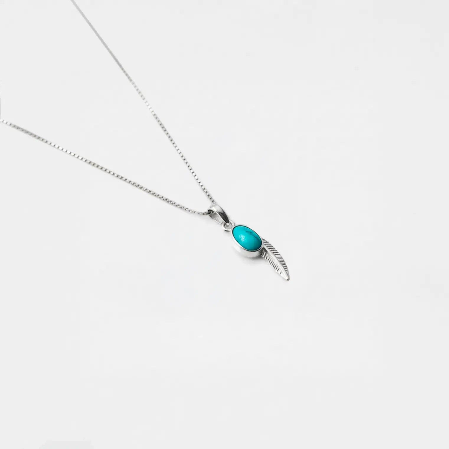 Necklace with a turquoise feather pendant on a white background