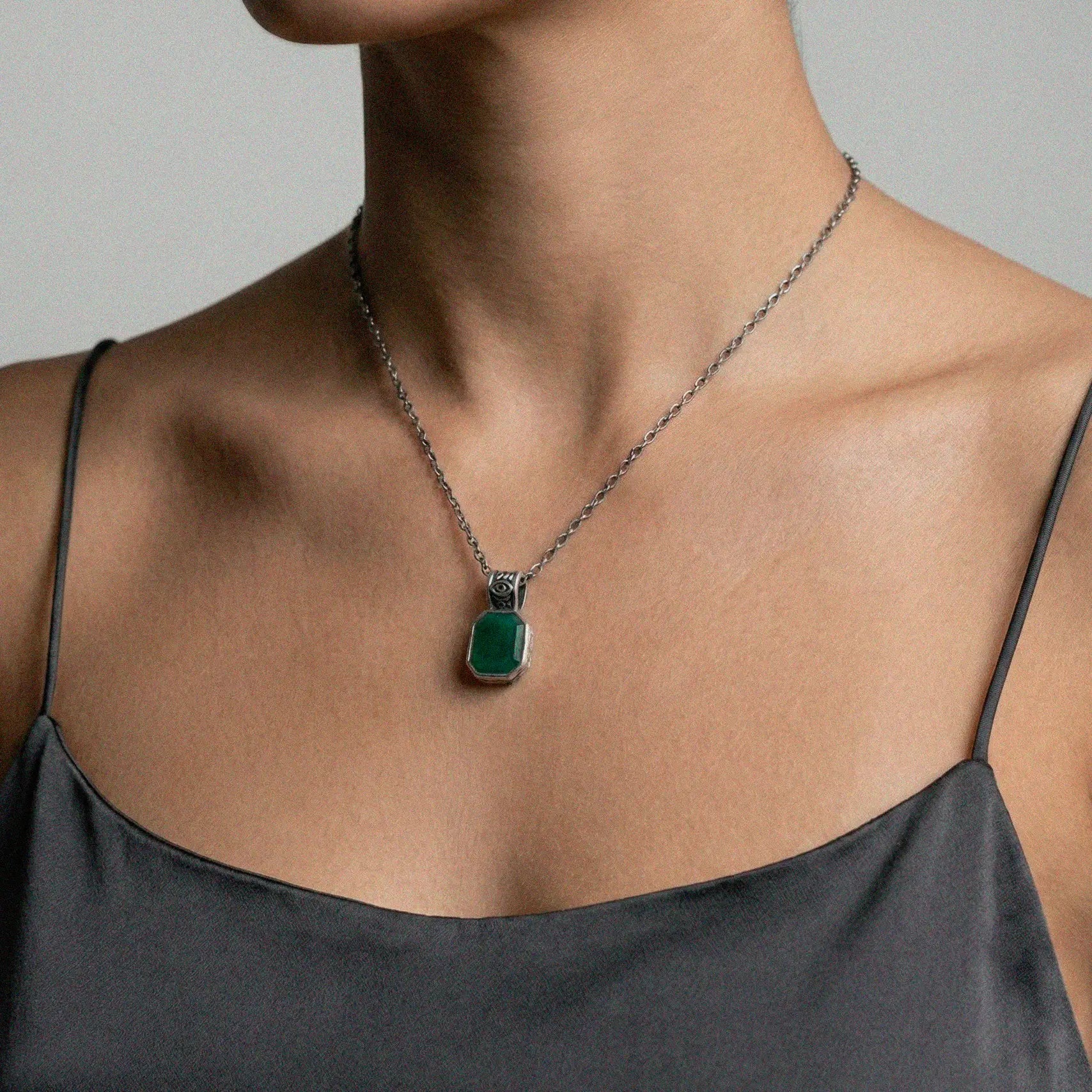 Necklace with a jadependant worn by a woman against a neutral background