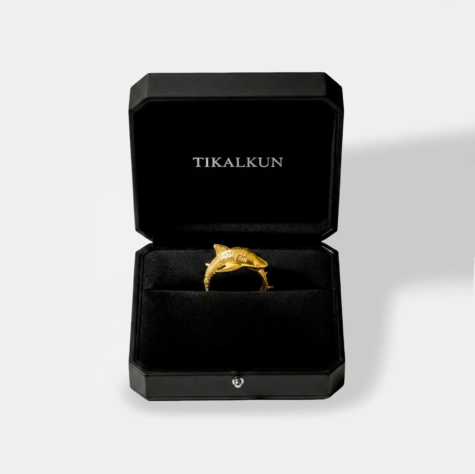 Gold tiger-shark ring in a black Tikalkun jewelry box on a light gray background