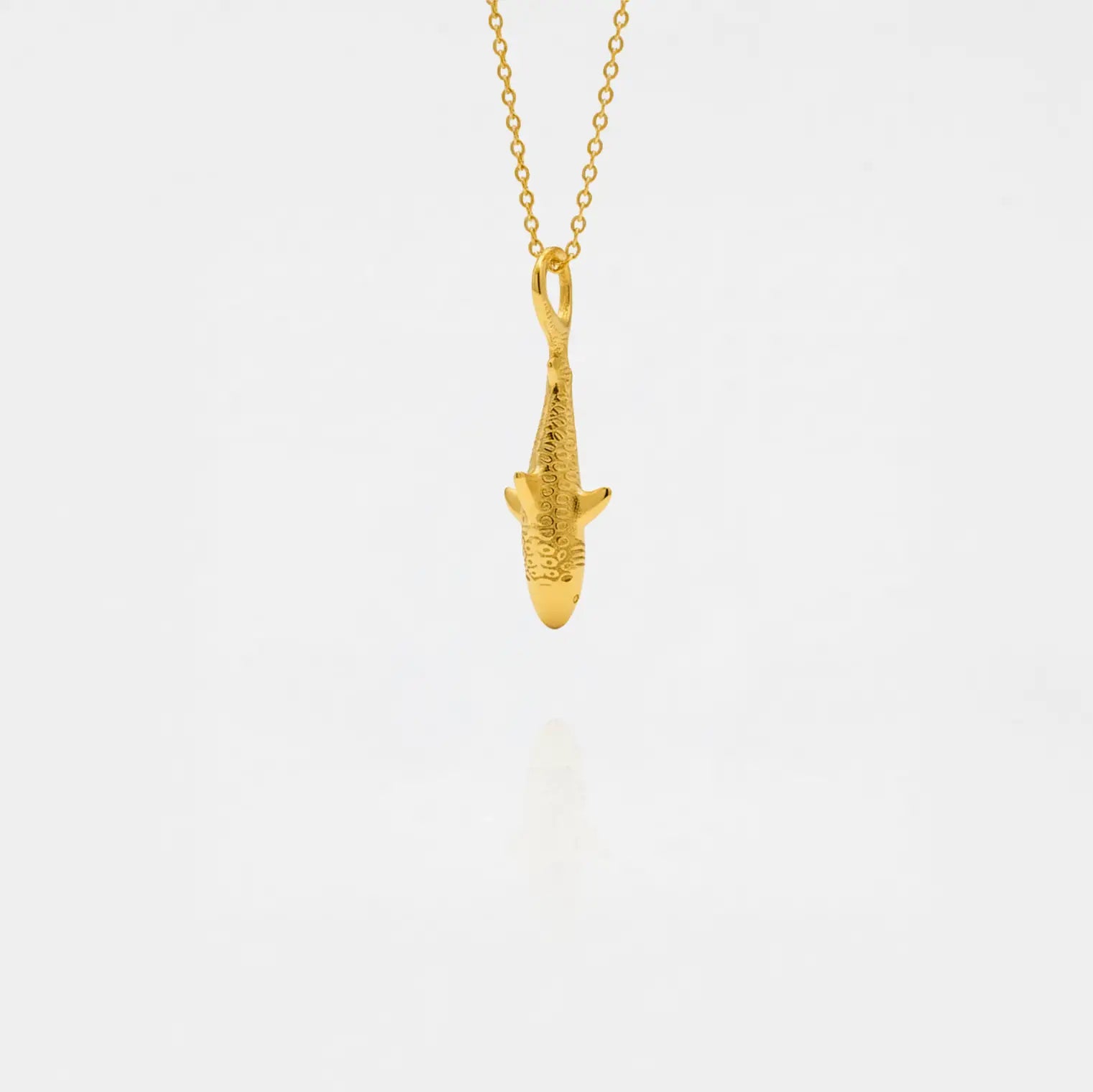 Gold tiger-shark pendant on a chain against a white background