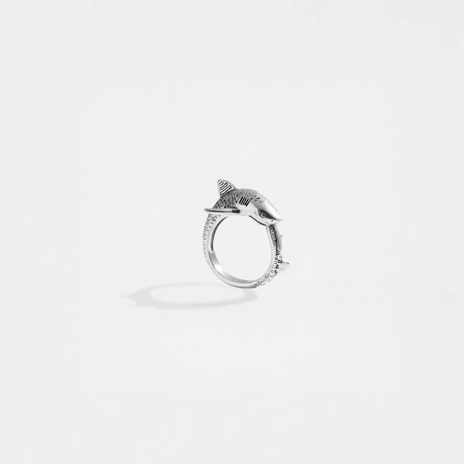 Silver ring with a tiger-shark design on a light gray background