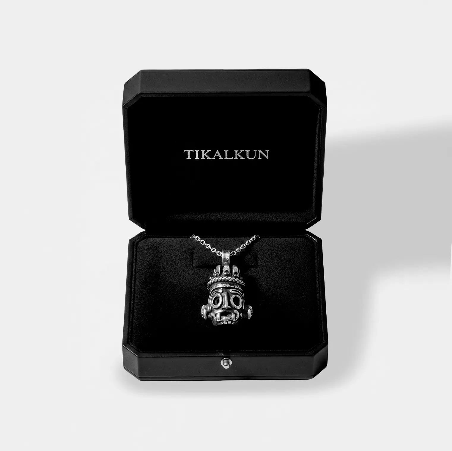 Silver tlaloc pendant necklace in a black Tikalkun jewelry box on a light gray background