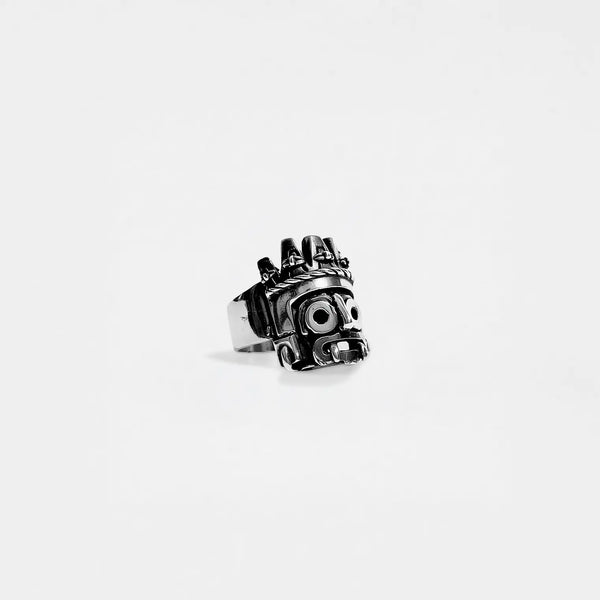 Metallic ring with a tlaloc design on a white background