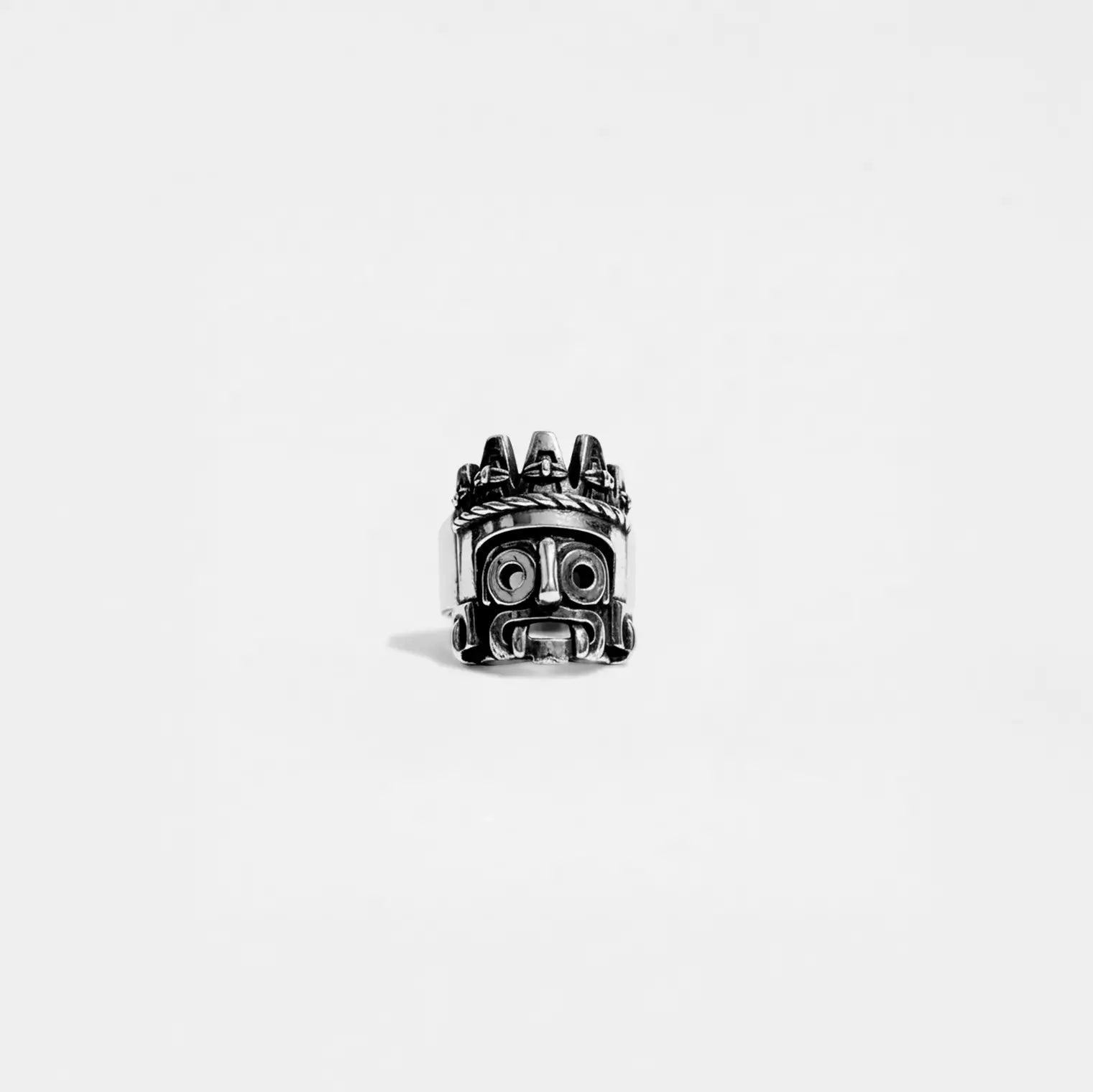 Silver ring with a tlaloc design on a white background