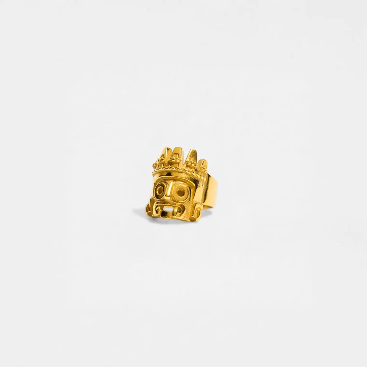 Gold ring with a tlaloc design on a white background