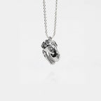 Silver dinosaur skull necklace on a white background