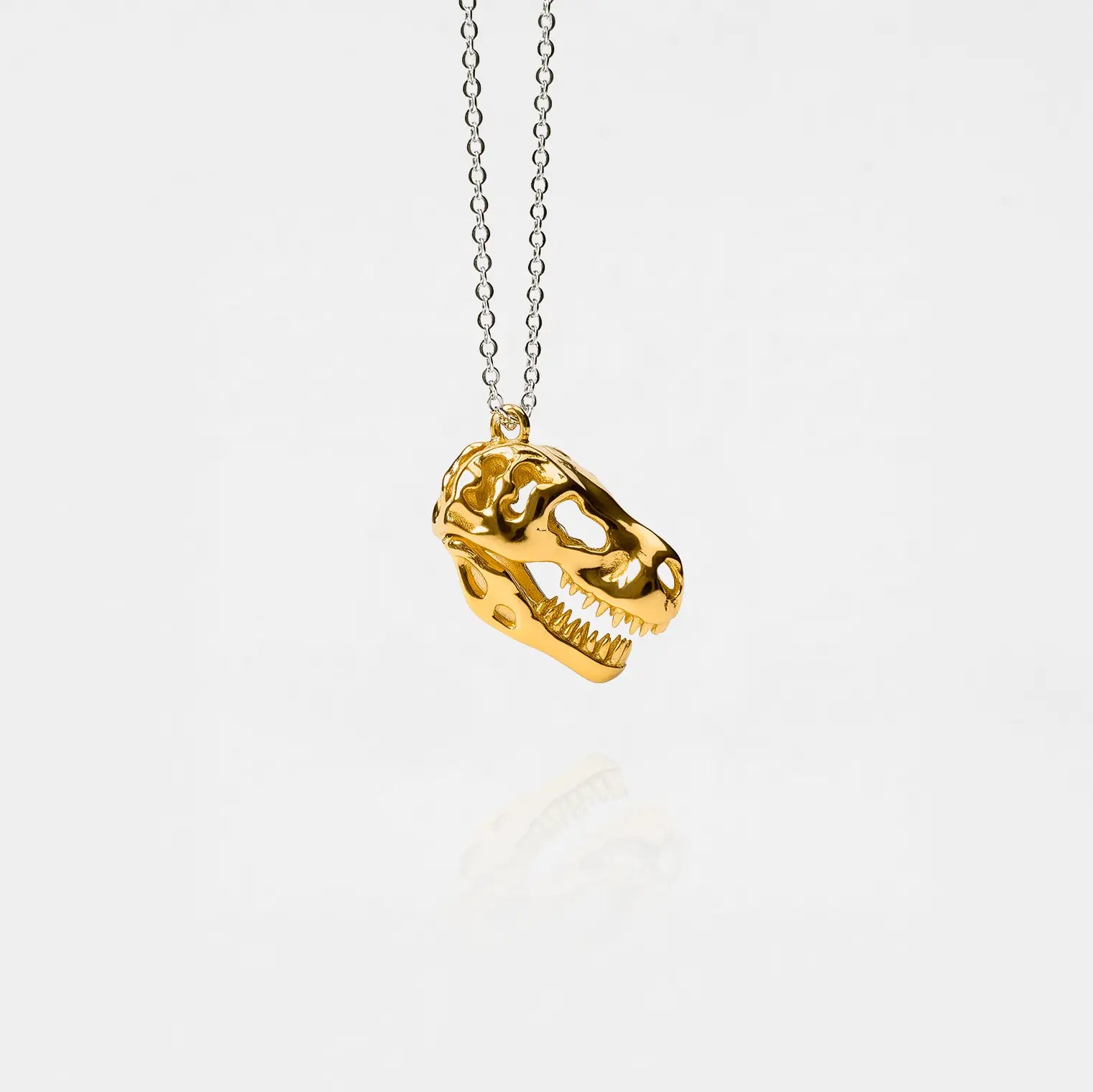 Gold dinosaur skull necklace on a white background