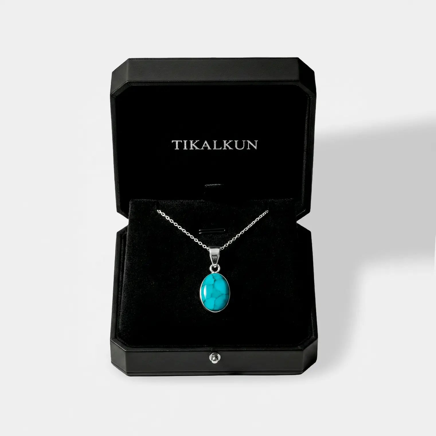 Turquoise pendant necklace in a black Tikalkun jewelry box on a white background