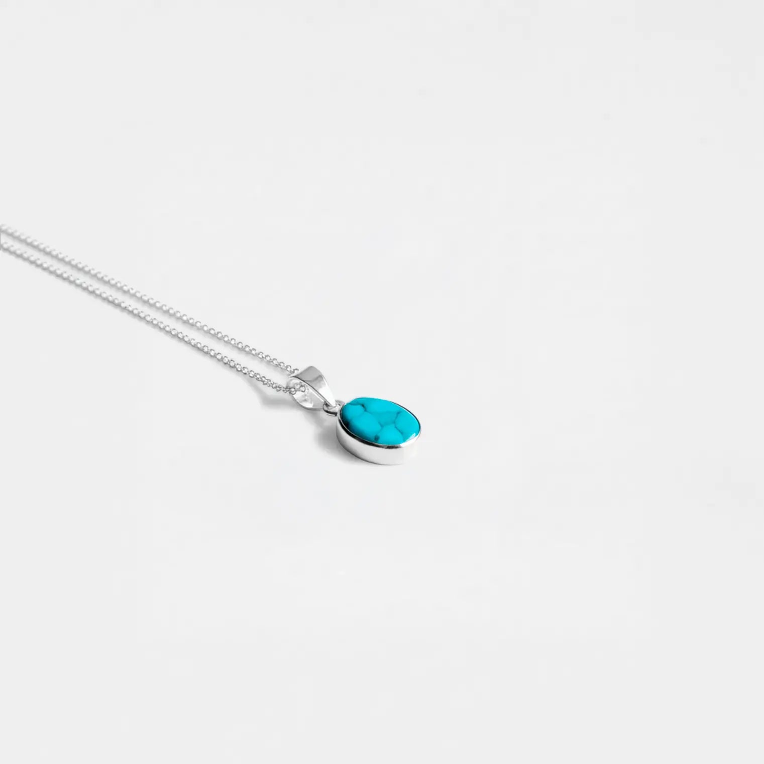 Silver necklace with a turquoise pendant on a white background