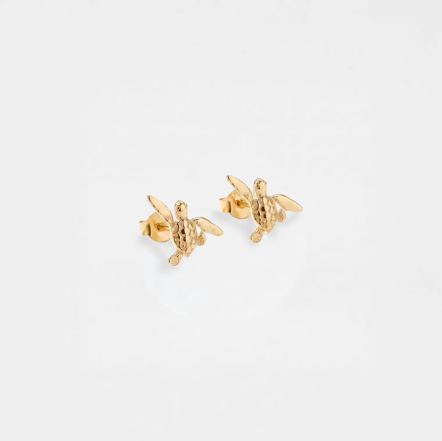 gold turtle earrings on a white background