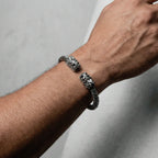 Silver bracelet with quetzalcoatl heads design on a wrist against a neutral background