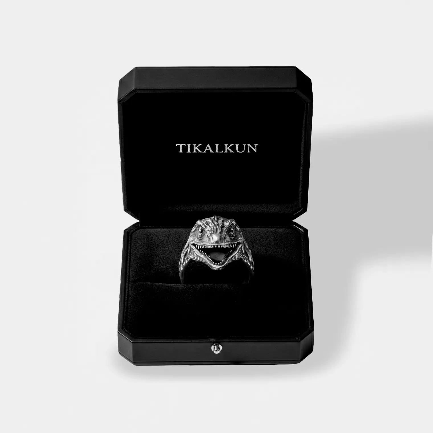 Silver velociraptor ring in a black Tikalkun jewelry box on a light gray background