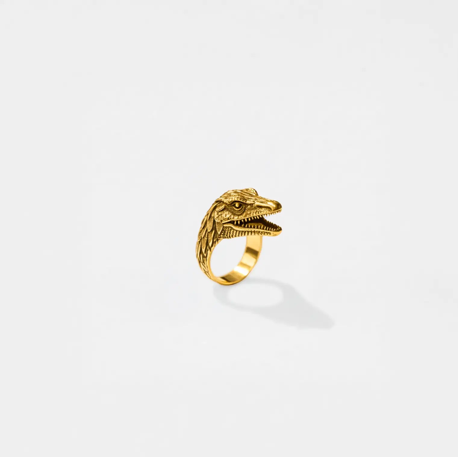 Gold dinosaur-shaped ring on a white background