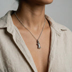 Necklace with a venus de milo pendant worn by a person against a neutral background