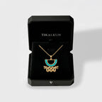 Jewelry box with an aztec gold necklace featuring a blue stone, branded 'TIKALKUN'.