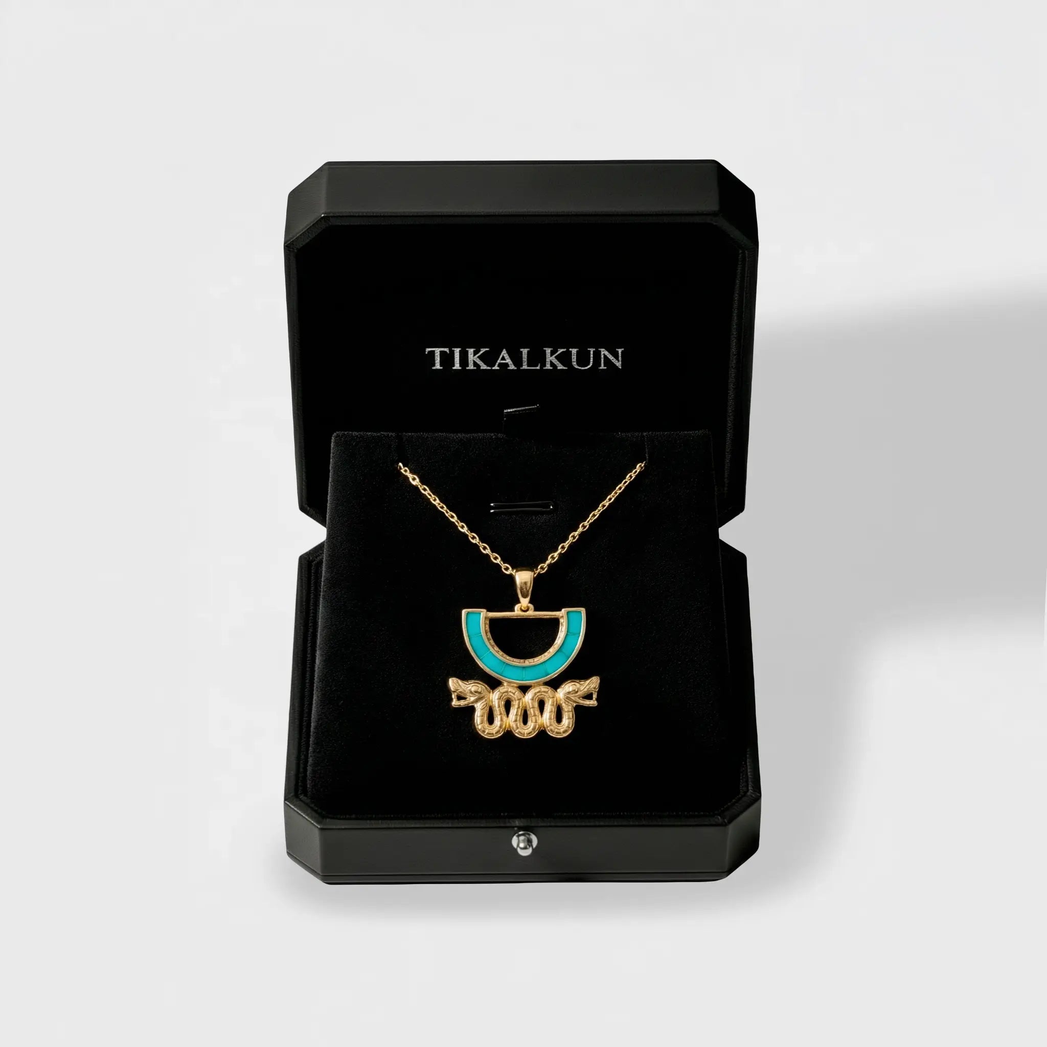 Jewelry box with an aztec gold necklace featuring a blue stone, branded 'TIKALKUN'.