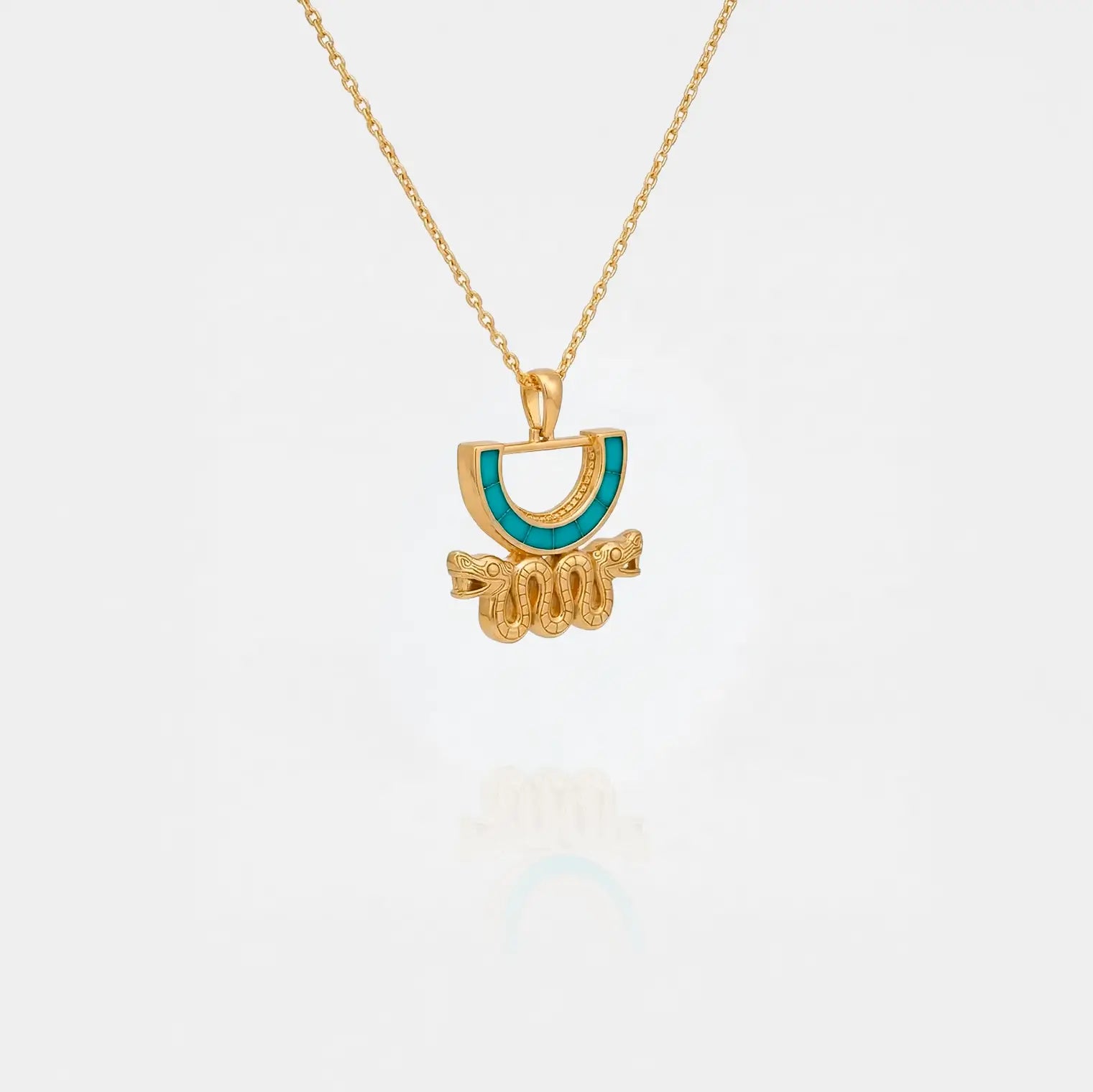 Gold aztec necklace with a half-circle pendant featuring turquoise color on a white background