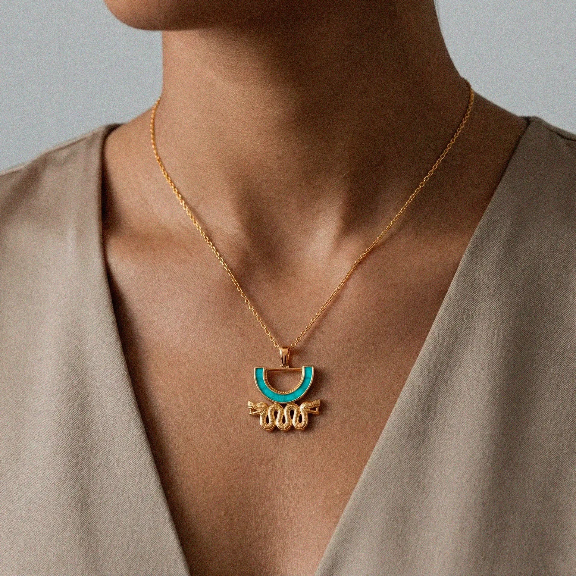 aztec Necklace with a gold pendant featuring a blue gemstone on a neutral background