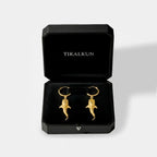 Gold whale-shark earrings in a black Tikalkun jewelry box on a light gray background