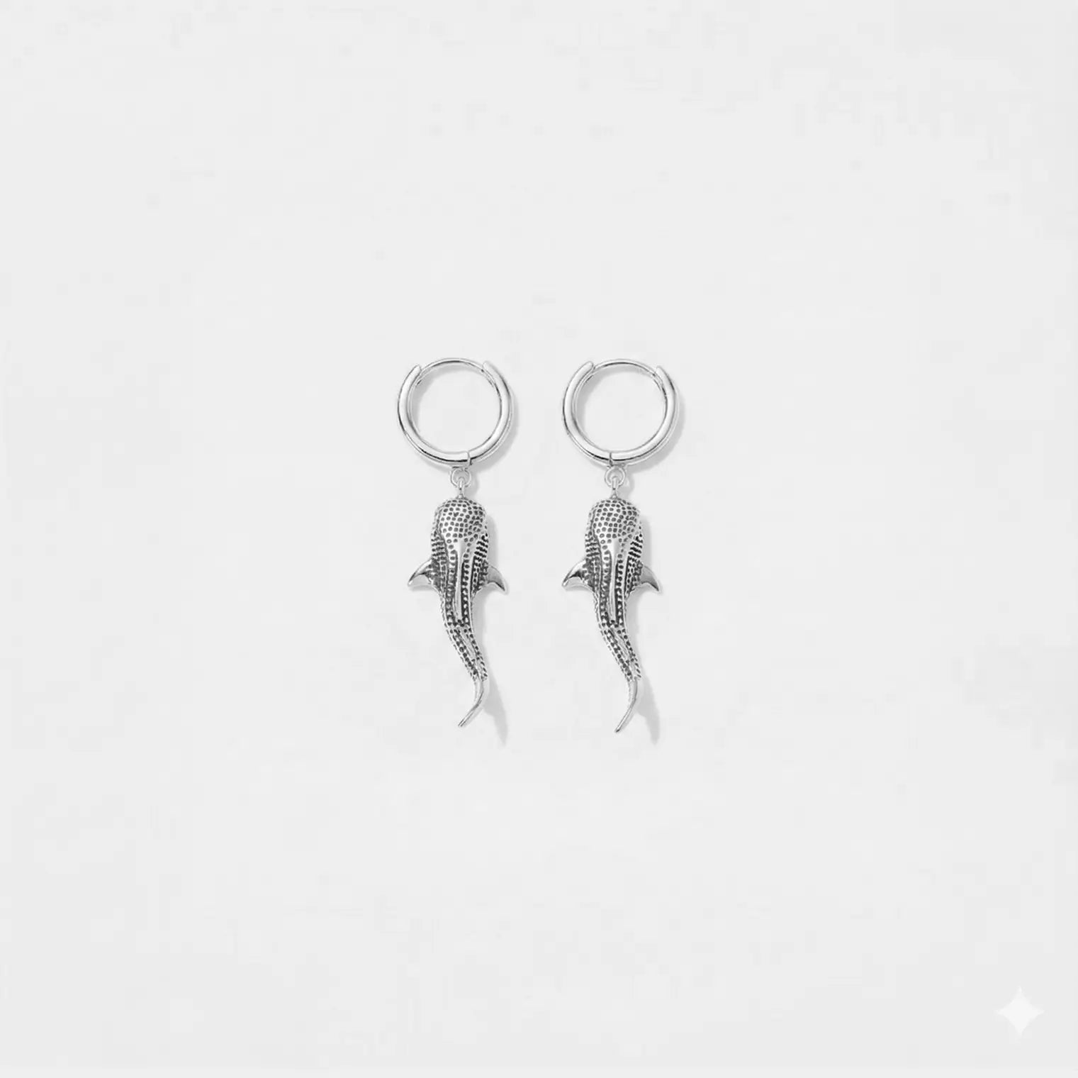Pair of silver whale-shark earrings on a white background