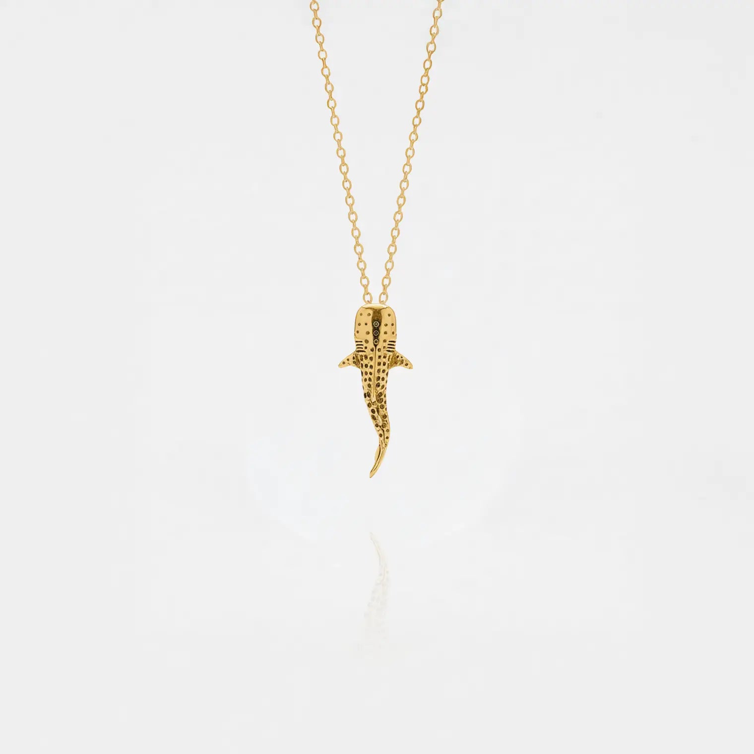 Whale-shark gold pendant on a white background