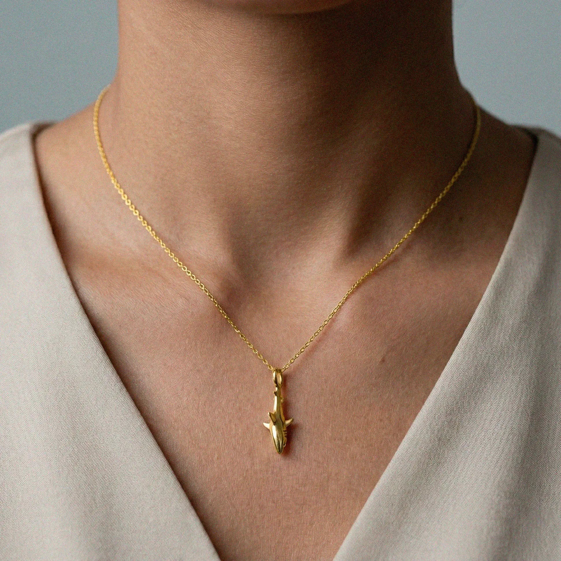 woman wearing white-shark gold pendant 