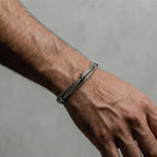 Silver bracelet on a person's wrist against a gray background